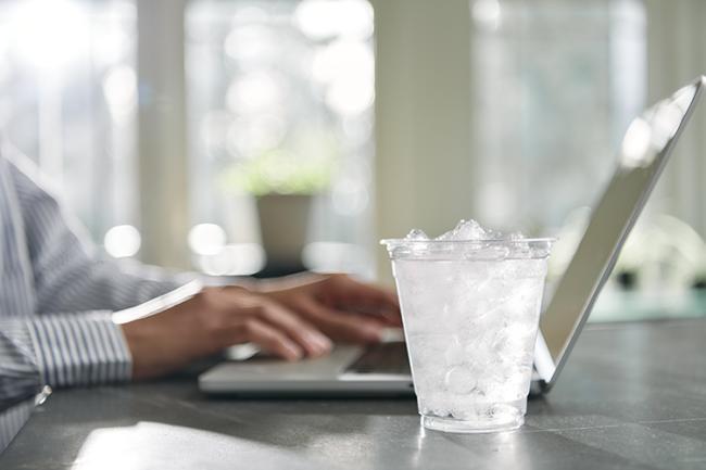 glass of water next to a laptop